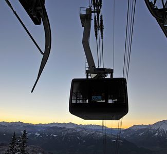 [Translate to englisch:] Seilbahn vor Bergpanorama bei Sonnenuntergang